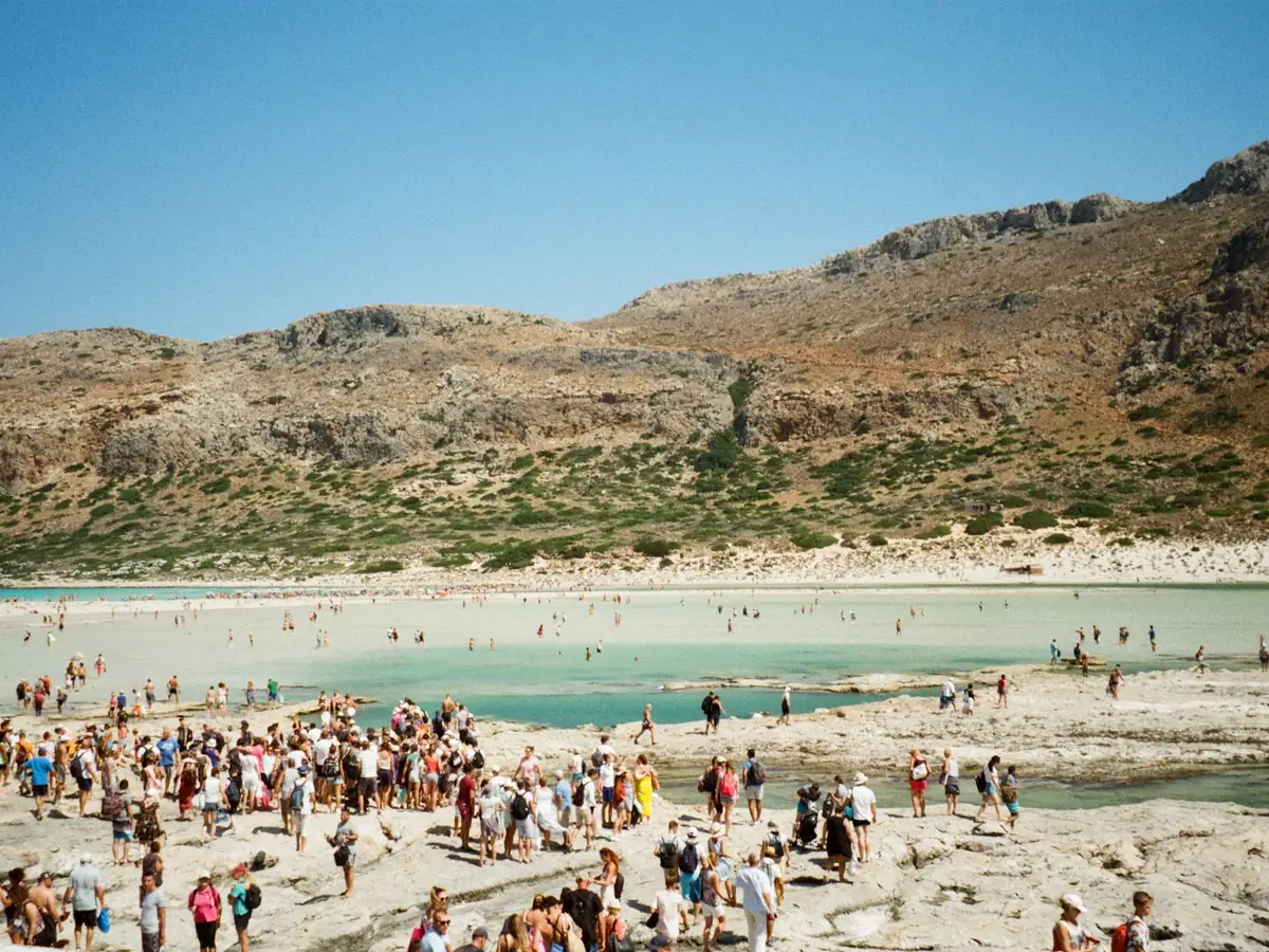 Badegjester i det grunne vannet på stranden i Balos med fjellene bak