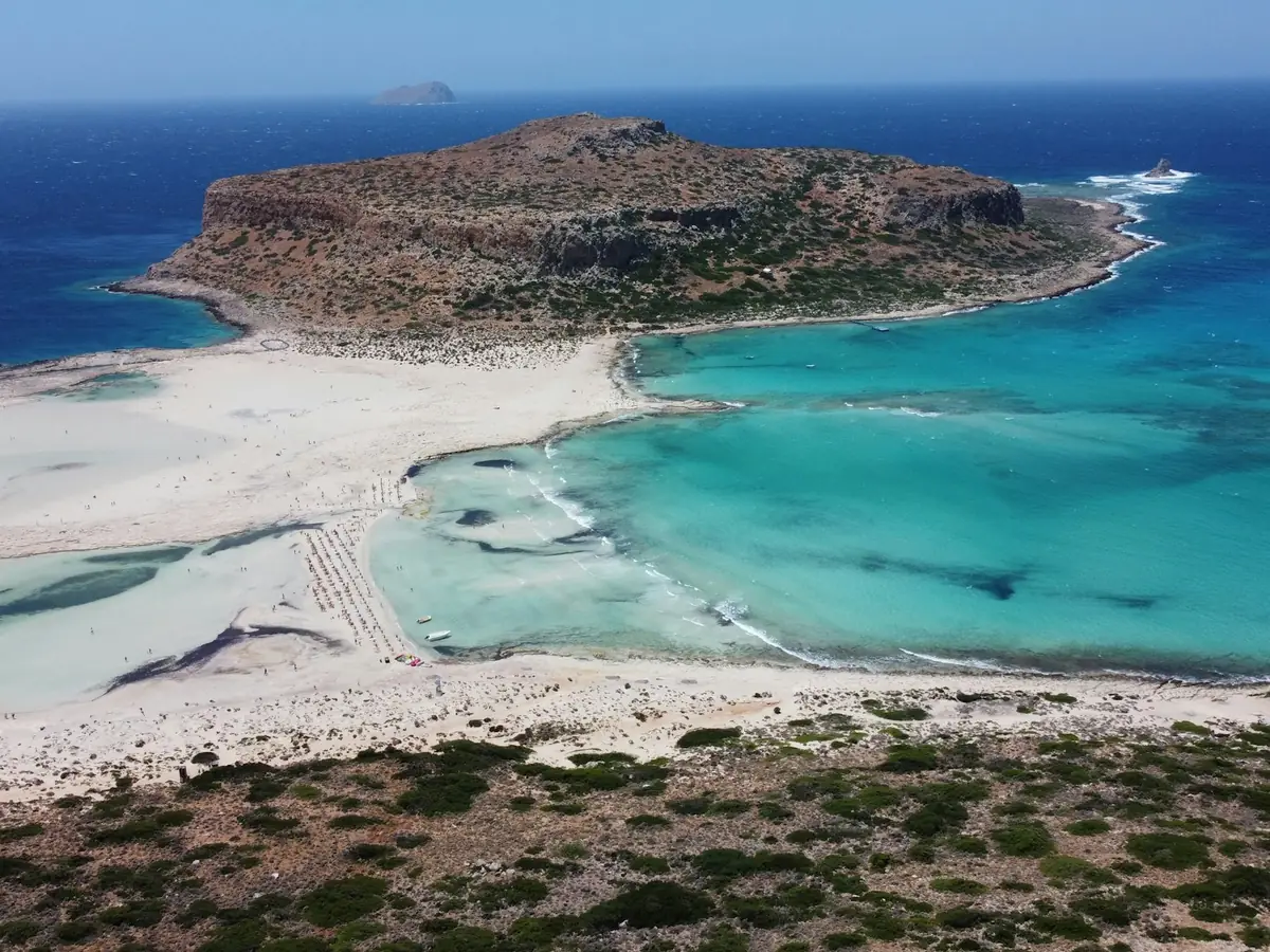 Balos-lagunen sett fra utsiktspunktet ovenfor, med vann i alle blåtoner og Gramvousa i bakgrunnen