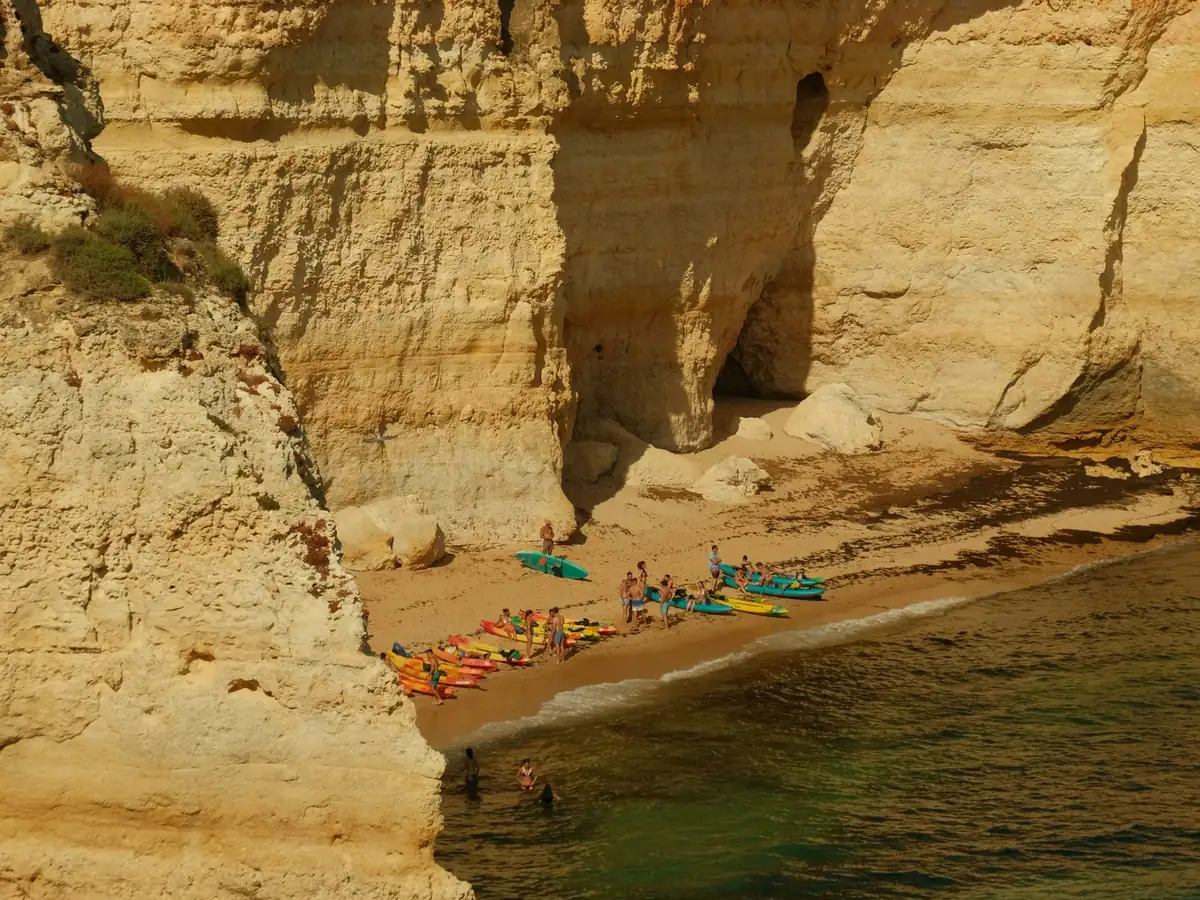 Fargerike kajakker på en liten strand under de gule kalksteinsklippene i Algarve